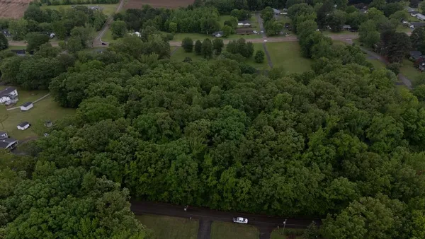 an aerial view of residential house with outdoor space and trees all around