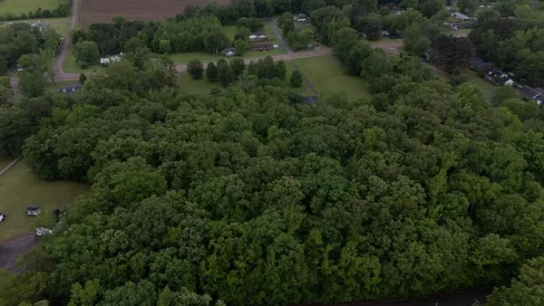 an aerial view of residential house with outdoor space and trees all around