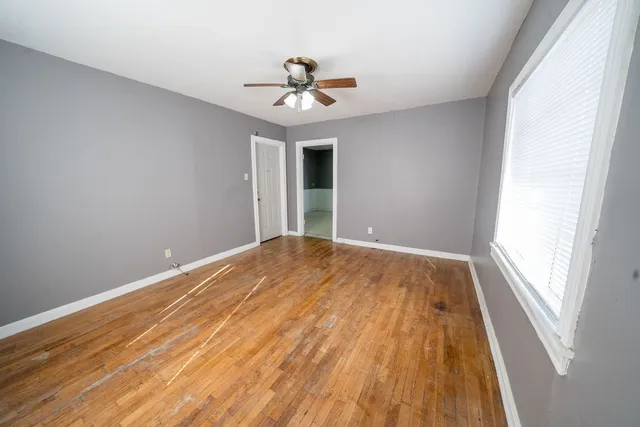 a view of empty room with wooden floor and fan