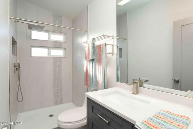 a bathroom with a sink vanity granite toilet and shower