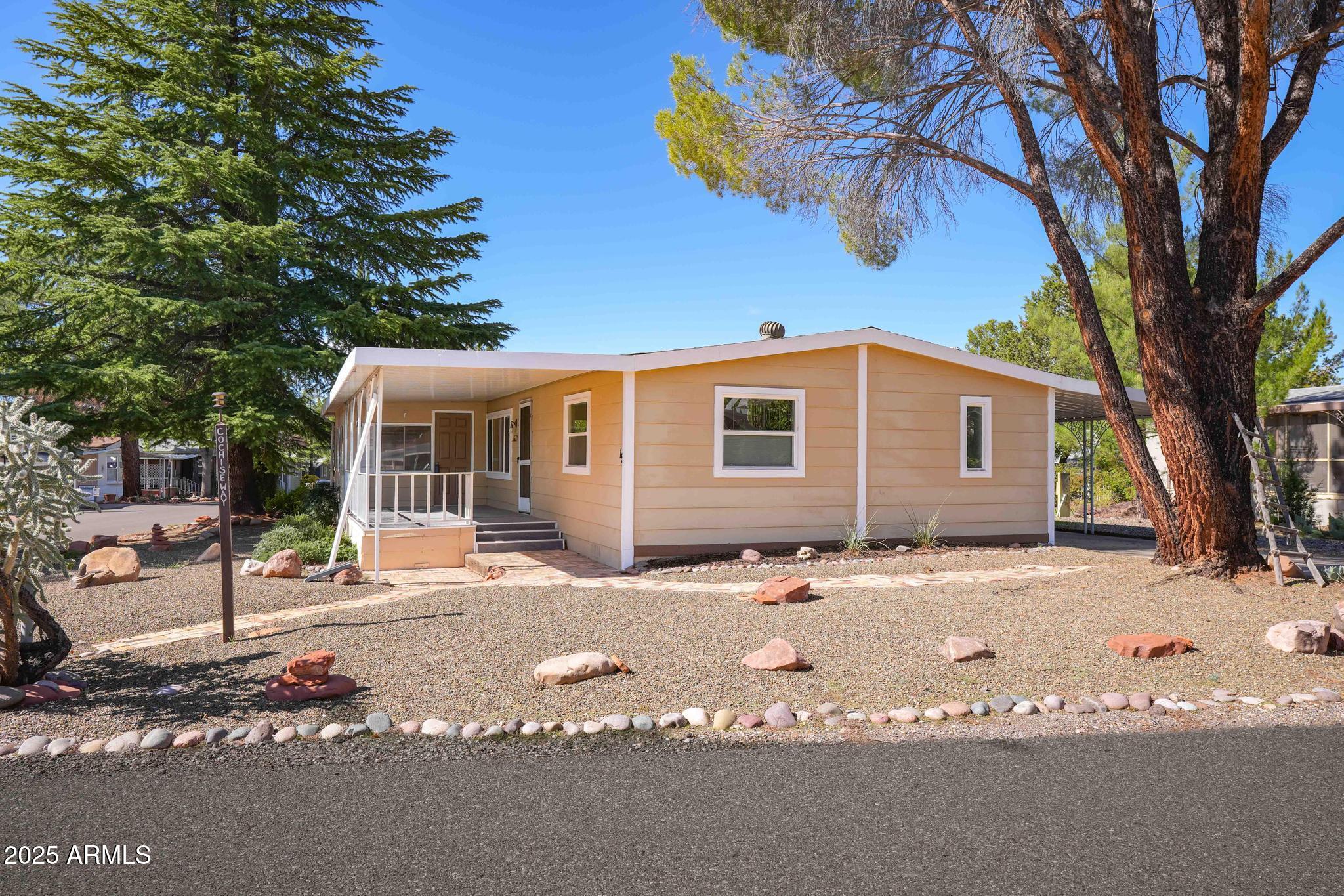 6770 West State Rte 89A, Unit 15 Sedona, AZ 86336 - Photo 2 of 27 a backyard of a house with table and chairs under an umbrella