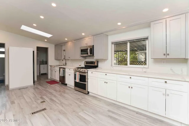 a kitchen with white cabinets and stainless steel appliances