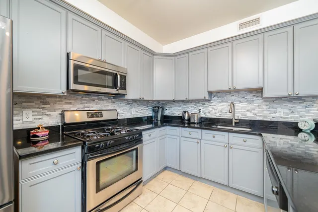 a kitchen with granite countertop white cabinets sink and stainless steel appliances