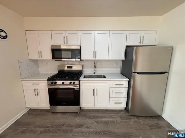 a kitchen with white cabinets and stainless steel appliances