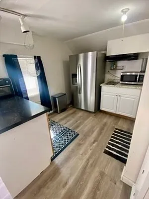 a kitchen with a refrigerator a stove and a sink with wooden floor