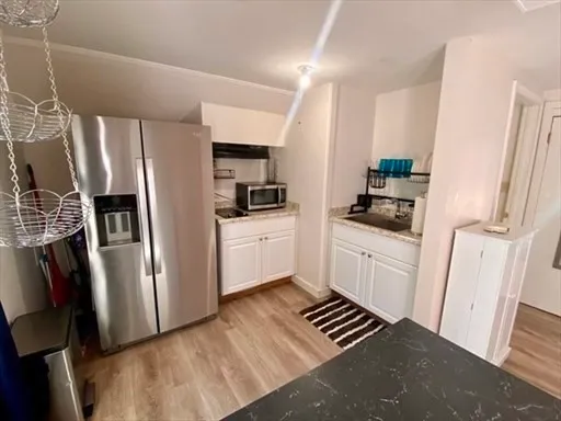 a kitchen with stainless steel appliances a refrigerator a sink and white cabinets