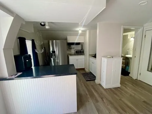 a view of a kitchen with refrigerator and wooden floor