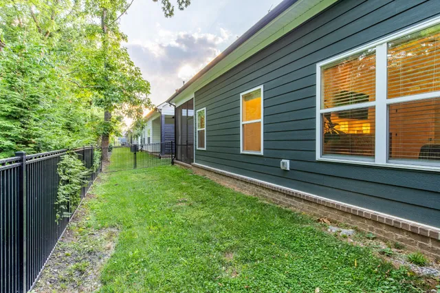a backyard of a house with plants and large tree