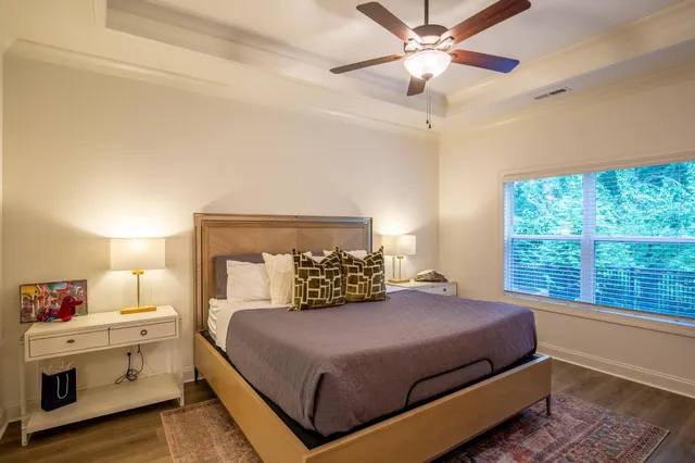 a bedroom with a large bed and a chandelier fan