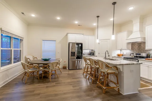 a kitchen with stainless steel appliances kitchen island granite countertop a table chairs sink and cabinets