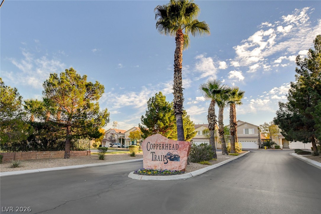 7259 Cestrum Road Las Vegas, NV 89113 - Photo 34 of 35 Discover the entrance to Copperhead Trails, a community marked by a stately stone sign amidst vibrant palm trees and mature landscaping.