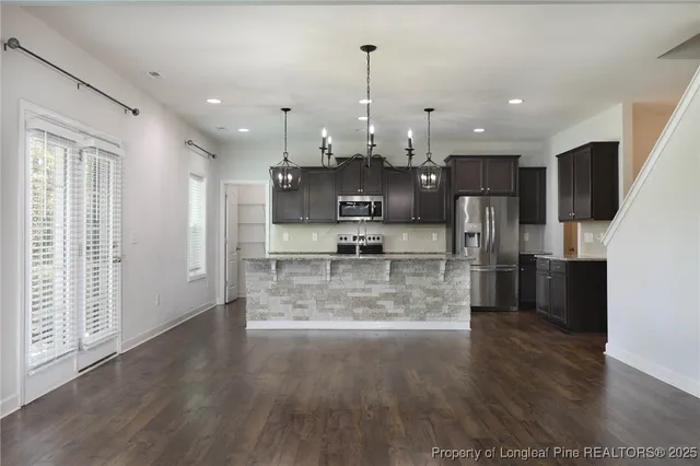 a view of a kitchen with stainless steel appliances wooden floor and a window