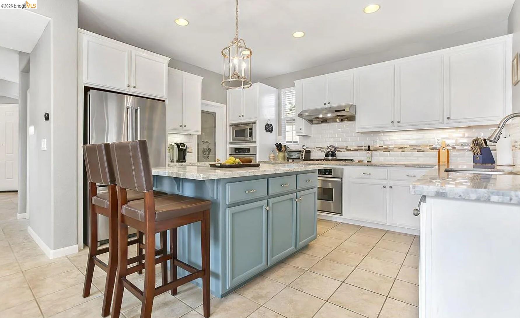 3251 Lookout Point Loop Discovery Bay, CA 94505 - Photo 3 of 31 Two tone kitchen with two tone cabinets, light stone countertops, a center island, light tile patterned floors, and backsplash