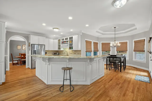 a kitchen with stainless steel appliances granite countertop a stove top oven a sink dishwasher a dining table and chairs with wooden floor