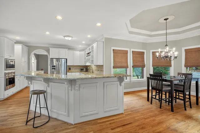 a kitchen with stainless steel appliances granite countertop a kitchen island a stove a table and chairs in it