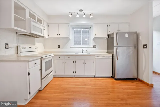 a kitchen with white cabinets and white appliances