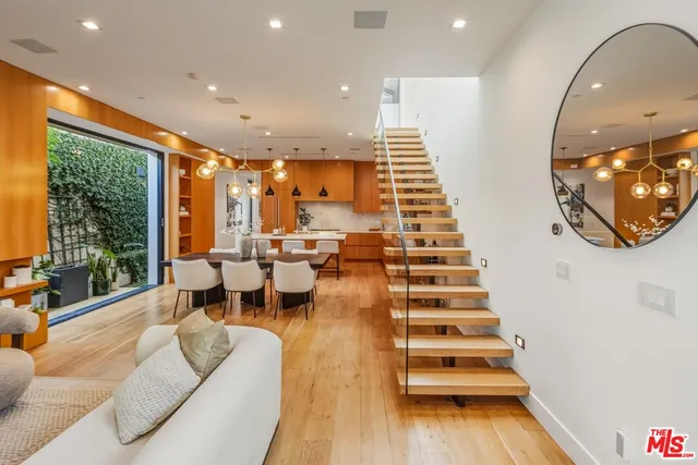 a living room with couches and dining table with wooden floor
