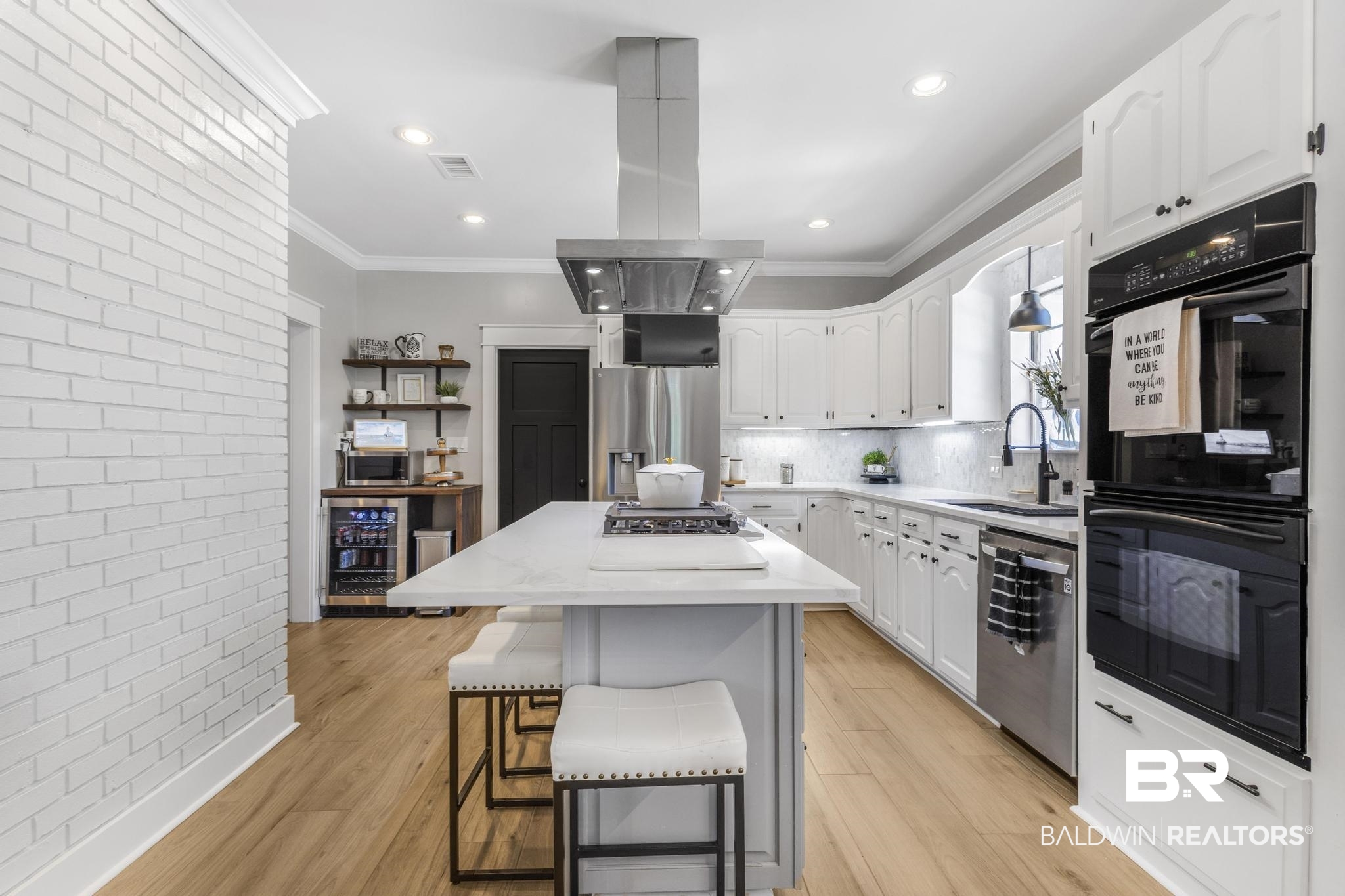 83 Caisson Trace Daphne, AL 36527 - Photo 19 of 63 Spacious kitchen featuring an expansive central island with seating, white cabinetry, integrated stainless steel appliances, and wood-finish flooring