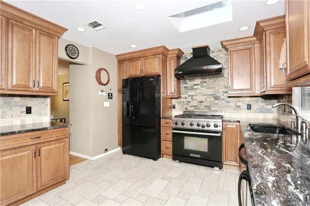 a kitchen with stainless steel appliances granite countertop a stove a sink and a refrigerator