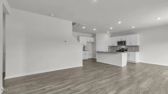 a view of kitchen with kitchen island granite countertop a stove top oven a sink and white cabinets