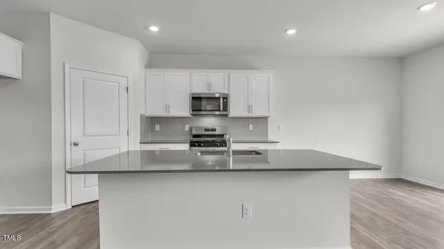 a kitchen with kitchen island granite countertop a sink a stove a microwave and wooden cabinets