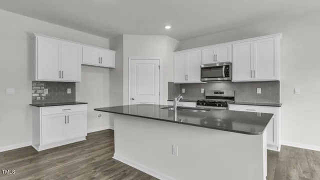 a large kitchen with granite countertop a sink a stove a microwave a counter space and cabinets