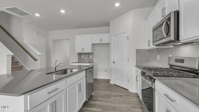 a kitchen with stainless steel appliances granite countertop a sink stove and cabinets