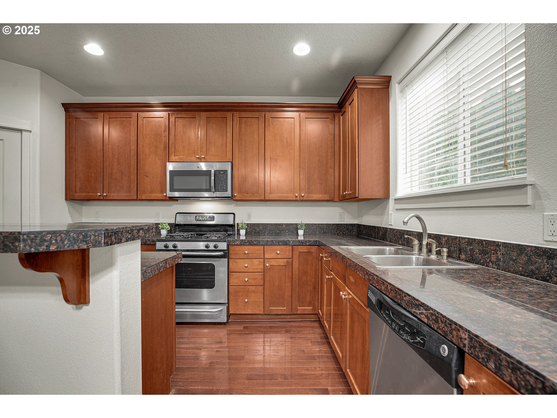 7110 Southwest Queen Lane Beaverton, OR 97008 - Photo 6 of 18 a kitchen with stainless steel appliances granite countertop a sink a stove and a microwave