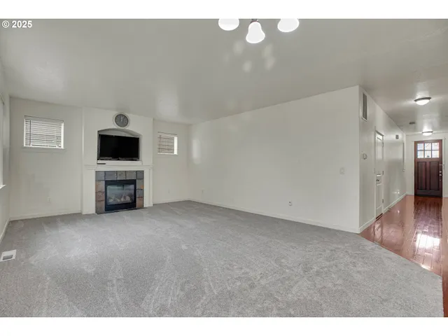 a view of an empty room with wooden floor and a fireplace