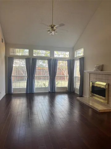 an empty room with wooden floor fireplace and windows