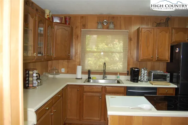 a kitchen with sink refrigerator and view of living room