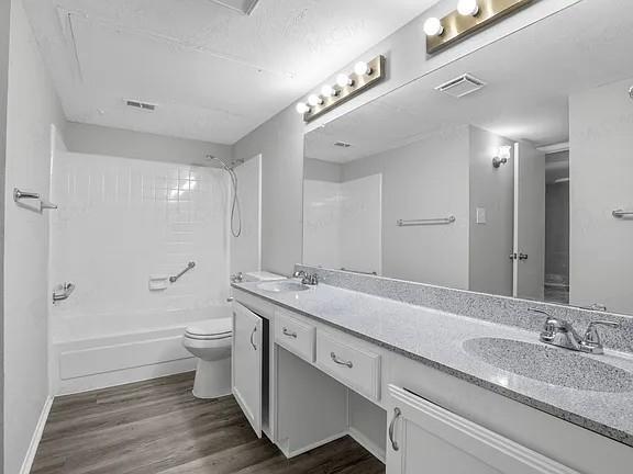 7129 Sorcey Road Dallas, TX 75249 - Photo 11 of 17 Bathroom with double vanity, dark wood-type flooring, shower combination, and a textured ceiling
