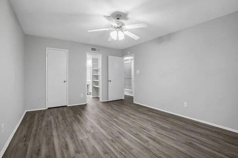 7129 Sorcey Road Dallas, TX 75249 - Photo 12 of 17 Unfurnished bedroom featuring a spacious closet, ceiling fan, and dark wood-style flooring