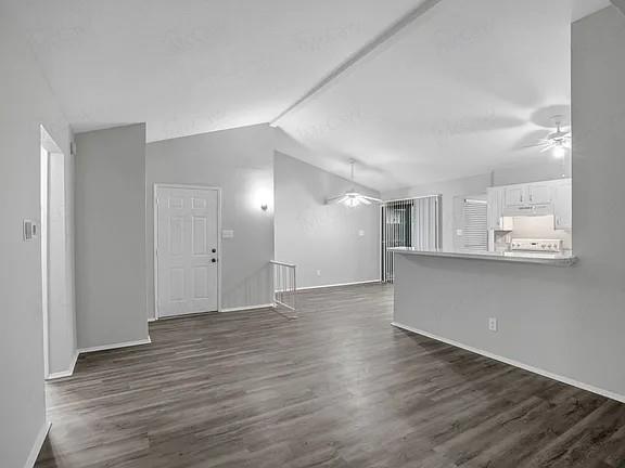 7129 Sorcey Road Dallas, TX 75249 - Photo 7 of 17 Unfurnished living room featuring lofted ceiling, dark wood-style flooring, and a ceiling fan