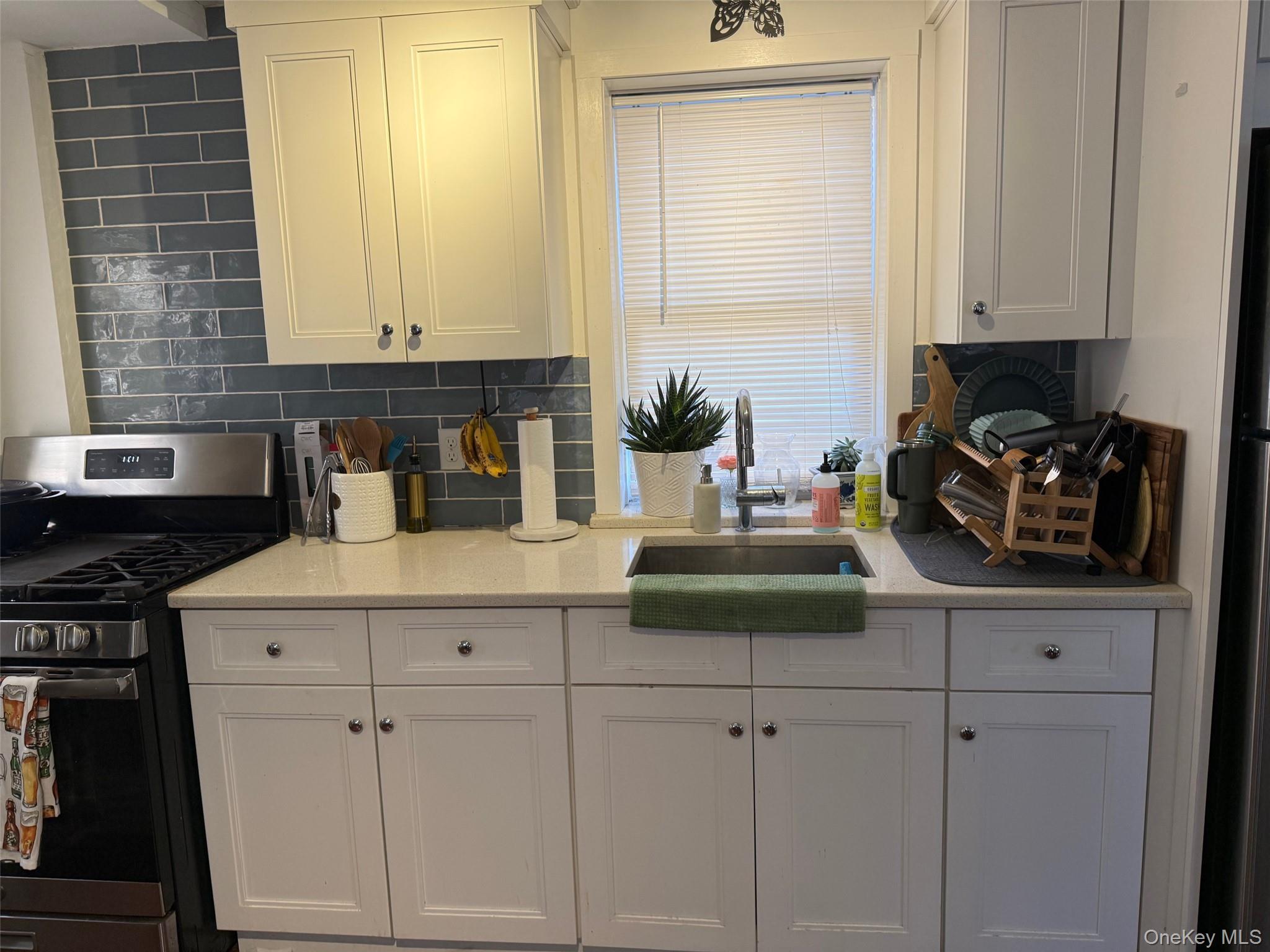 93 Jackson Avenue, Unit 1 Nyack, NY 10960 - Photo 1 of 10 Kitchen with stainless steel gas range, light stone counters, tasteful backsplash, and white cabinets