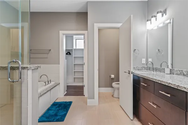 a spacious bathroom with a granite countertop sink a toilet a mirror and shower