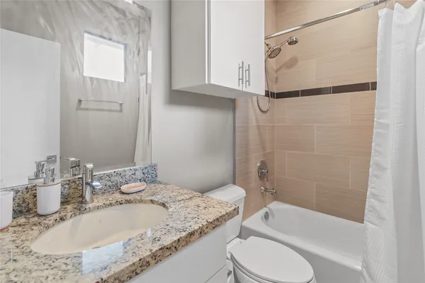a bathroom with a granite countertop sink toilet and shower