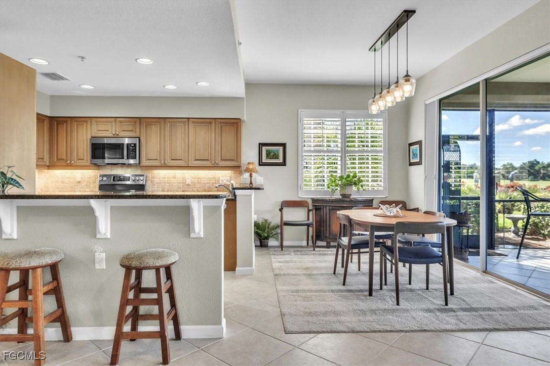 3711 Pebblebrook Ridge Court, Unit 101 Fort Myers, FL 33905 - Photo 11 of 50 a kitchen with kitchen island granite countertop wooden cabinets and a dining table