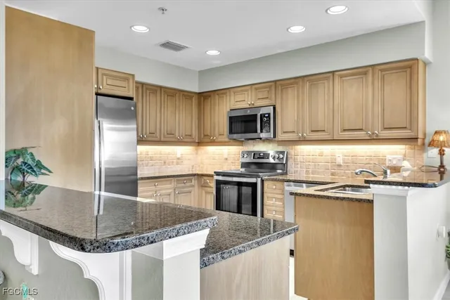 a kitchen with stainless steel appliances granite countertop a refrigerator a sink a stove a microwave and island