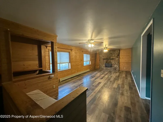 a view of empty room with wooden floor and fan