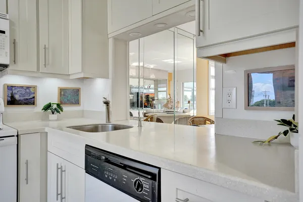 a kitchen with stainless steel appliances granite countertop a sink a stove and white cabinets with wooden floor