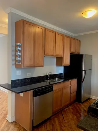 a kitchen with granite countertop wooden cabinets and a refrigerator