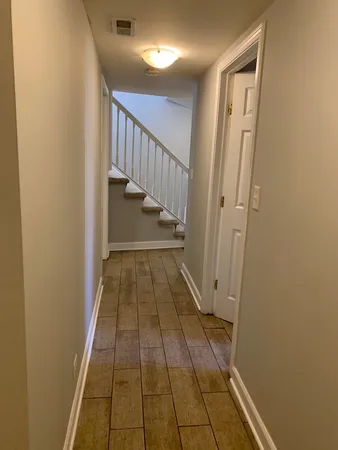 a view of a hallway with wooden floor and staircase