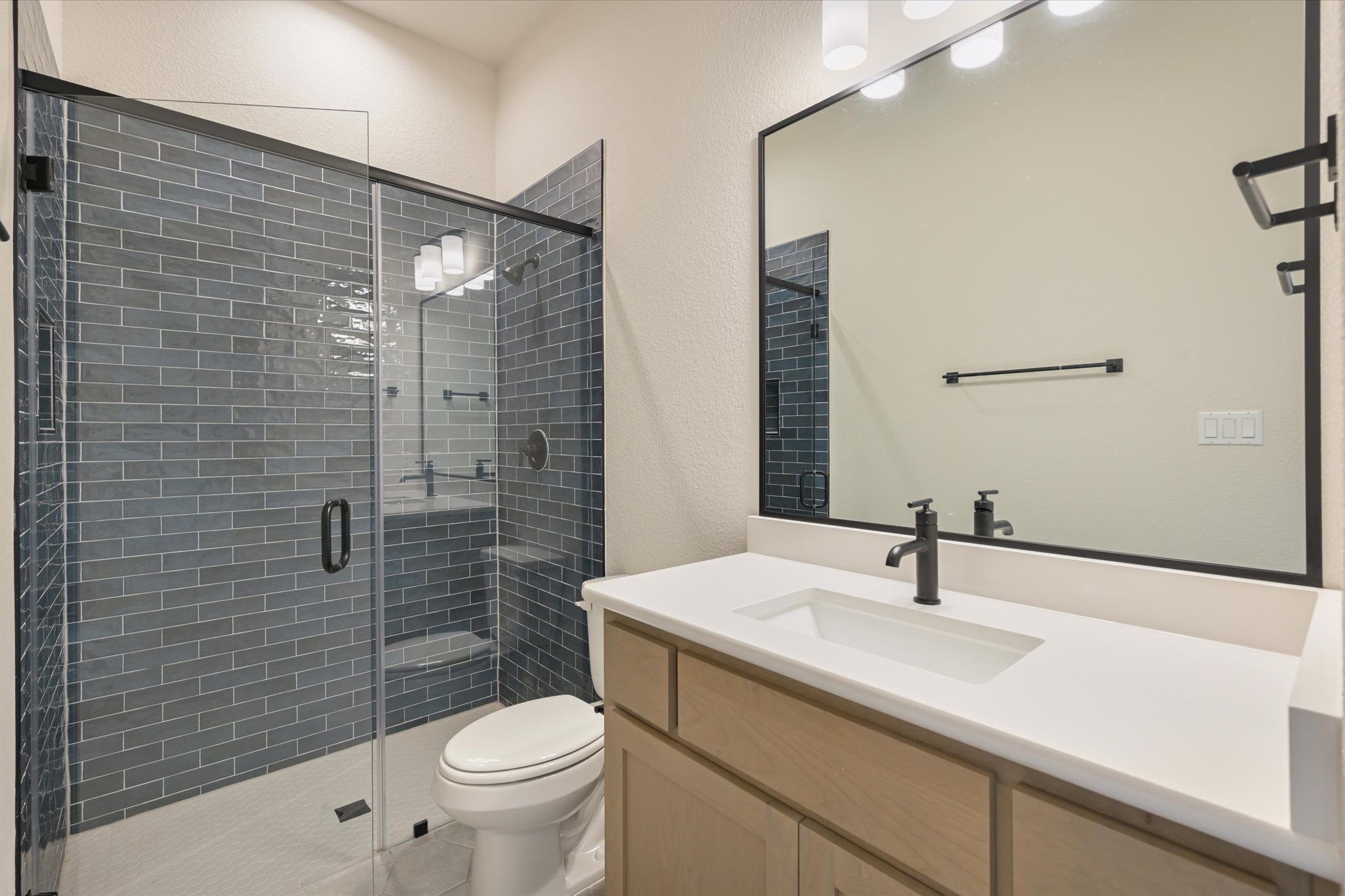 913 Presa Arriba Road Austin, TX 78733 - Photo 25 of 30 A well-appointed bathroom features a spacious glass-enclosed shower and a modern vanity with a single basin sink.
