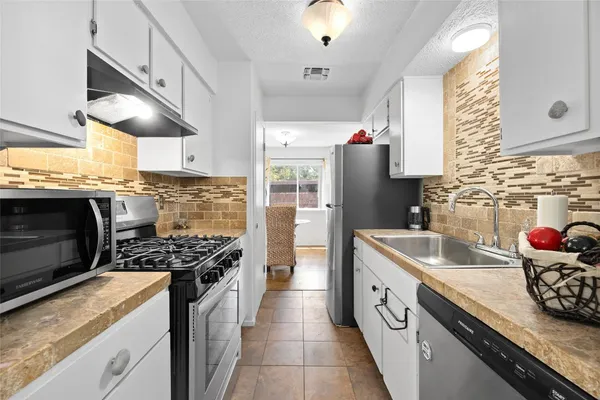 a kitchen with stainless steel appliances granite countertop a sink stove and cabinets