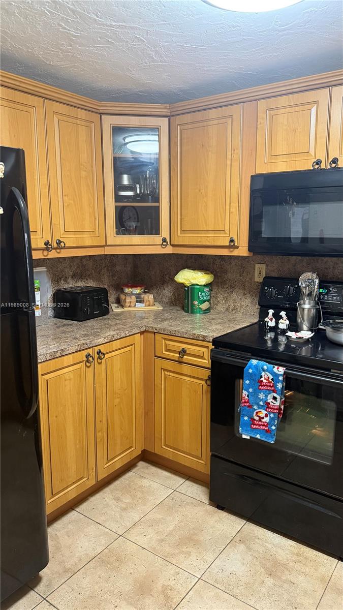 11207 Southwest 88th Street, Unit 216A Miami, FL 33176 - Photo 8 of 9 a kitchen with granite countertop a stove a sink and a microwave