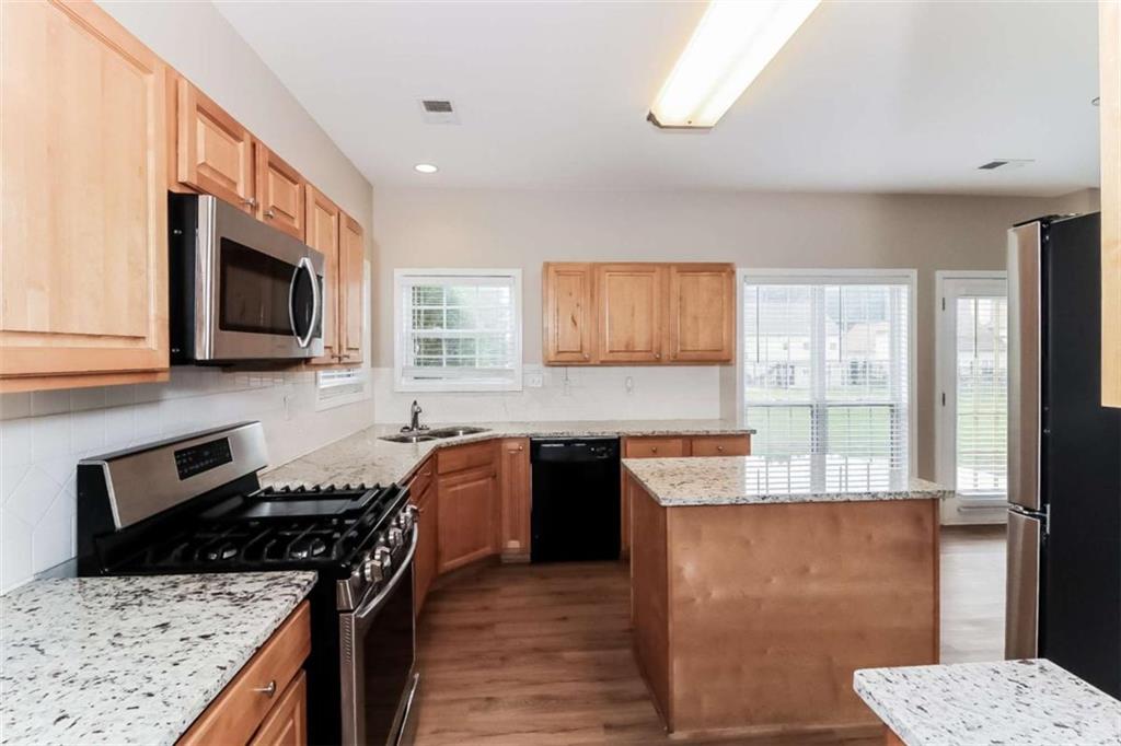 445 Fitzgerald Place Atlanta, GA 30349 - Photo 7 of 15 a kitchen with stainless steel appliances granite countertop a stove top oven a sink a counter space and cabinets