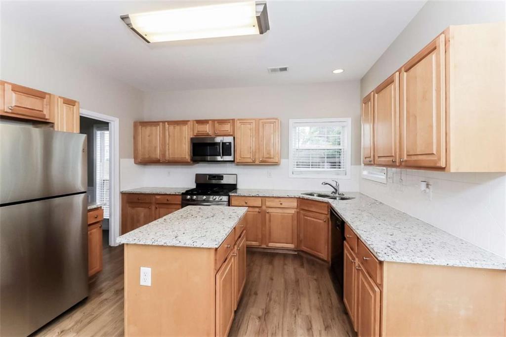 445 Fitzgerald Place Atlanta, GA 30349 - Photo 8 of 15 a kitchen with granite countertop stainless steel appliances a refrigerator a sink a stove top oven a counter space and cabinets