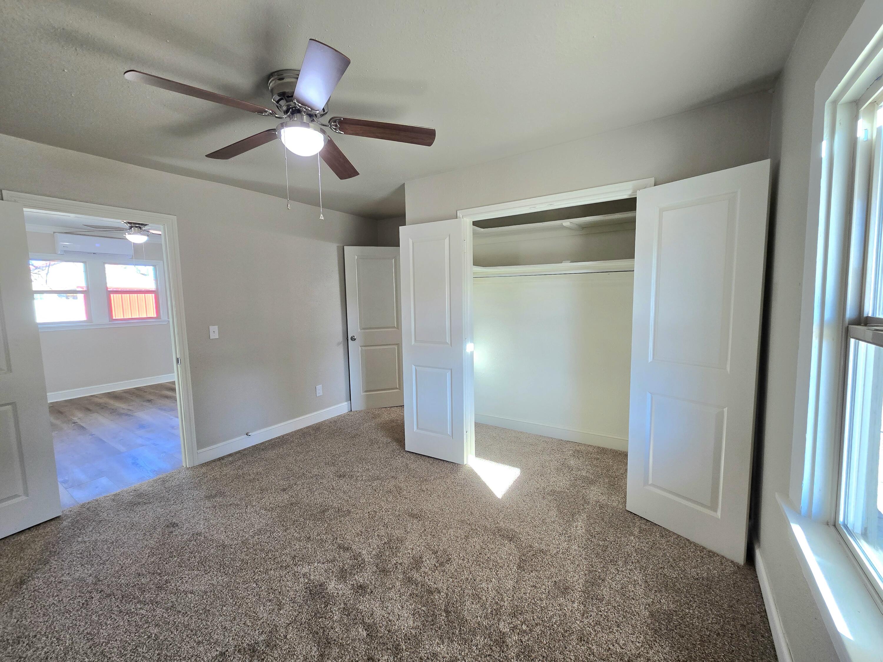 315 North Floyd Avenue Tulia, TX 79088 - Photo 13 of 24 an empty room with wooden floor fan and windows
