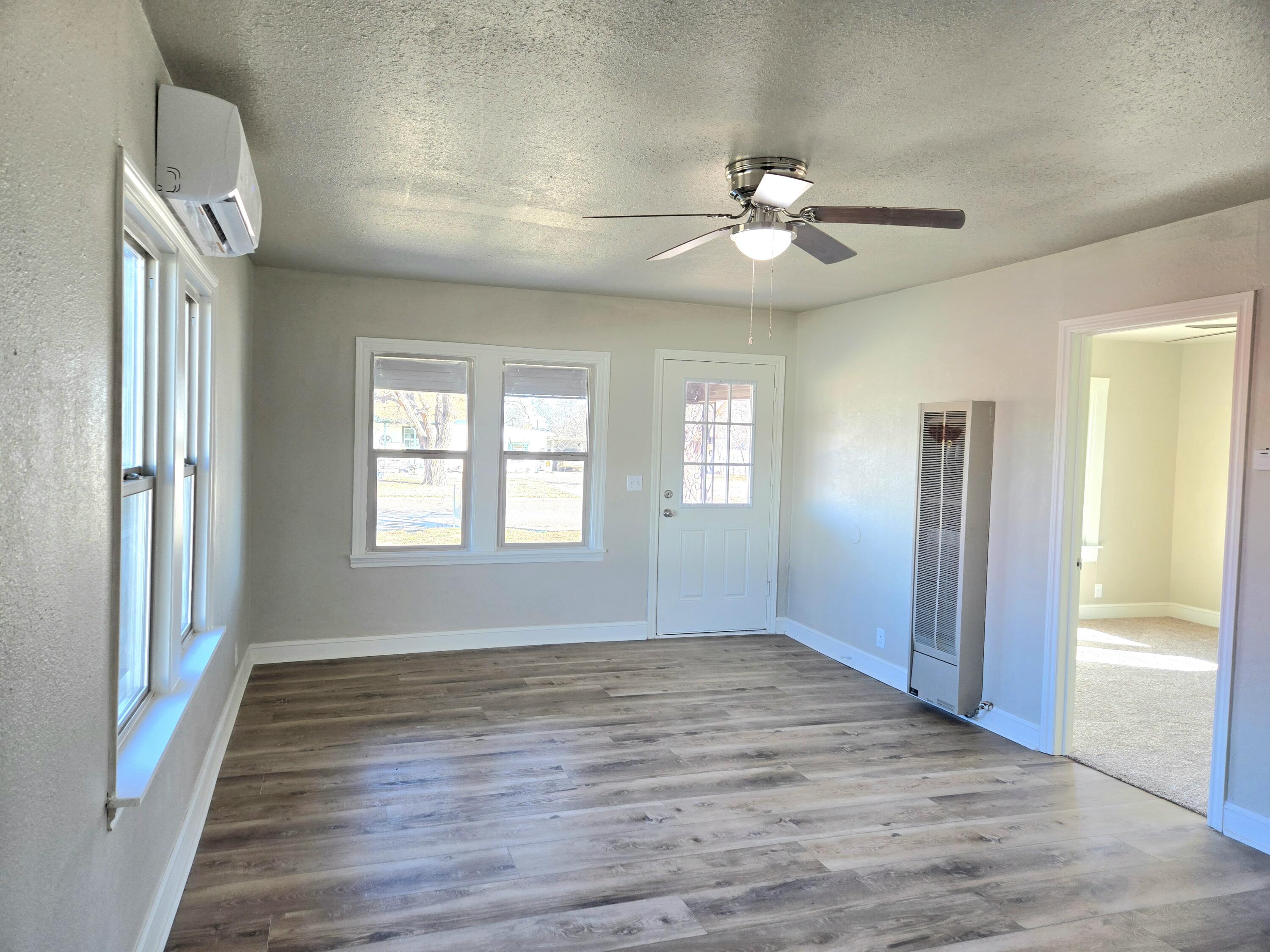 315 North Floyd Avenue Tulia, TX 79088 - Photo 6 of 24 an empty room with wooden floor fan and windows
